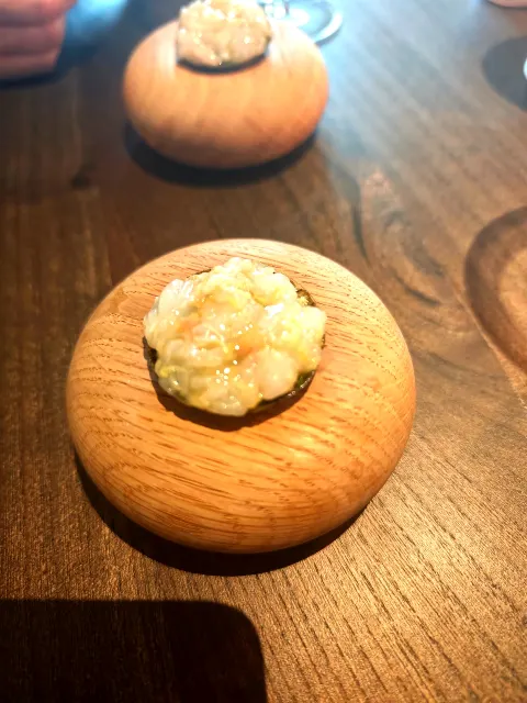 Une minuscule bouchée incroyablement fine présentée sur du bois.